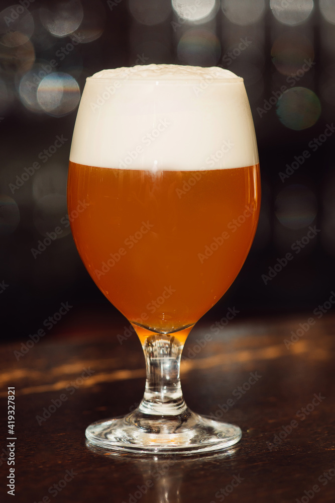 A glass of beer on the table in a dark bar. Background bokeh. A glass of beer on the table in a dark bar. Background bokeh.