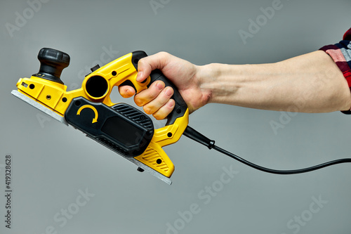 yellow electric wood planer slicer cutting machine isolated on gray background. carpentry construction diy concept
