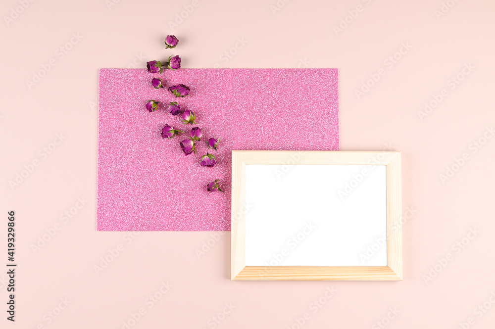 Wooden photo frame with white blank card and dry rosebuds on pastel pink background. Mock up poster frame. Stylish template Wooden photo frame with white blank card and dry rosebuds on pastel pink background. Mock up poster frame. Stylish template
