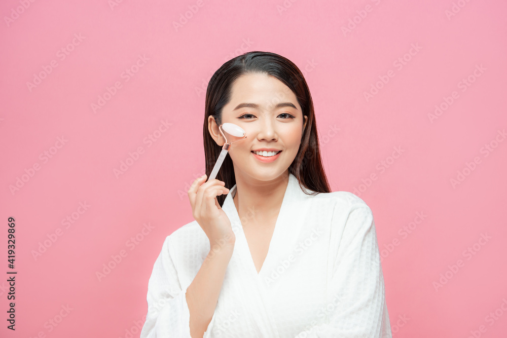 Beauty face care. Woman doing face massage with rose quartz face roller for spa skin care treatment at home Beauty face care. Woman doing face massage with rose quartz face roller for spa skin care treatment at home