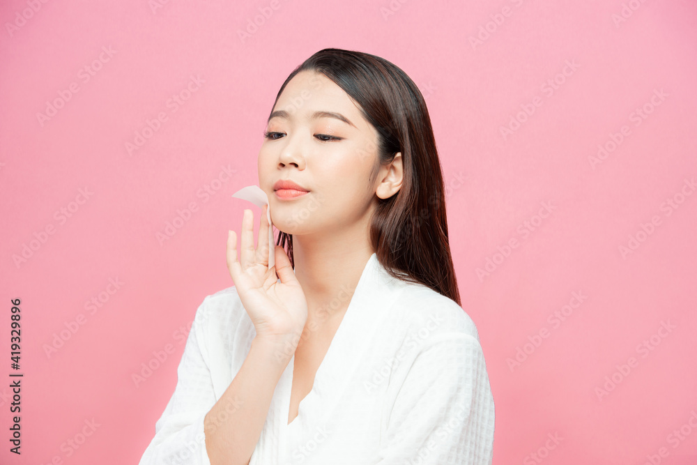 Woman using facial oil blotting paper. Photo of woman with perfect makeup on pink background. Beauty concept Woman using facial oil blotting paper. Photo of woman with perfect makeup on pink background. Beauty concept