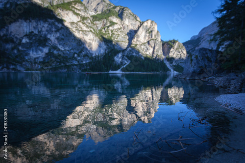 Tilt shift effect of reflections of dolomitic mountains on the Braies lake crystalline waters, South Tyrol, Italy. Concept: relaxation in nature, famous natural places, film sets, tilt shift effect