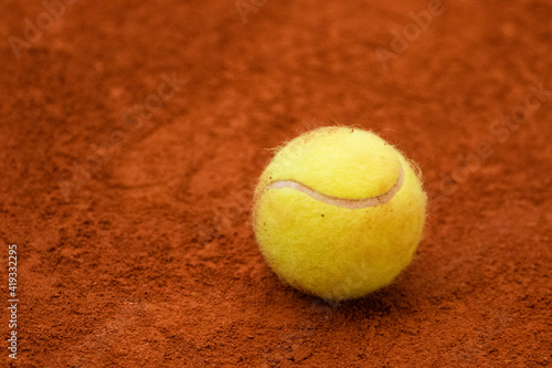Tennis ball in classic fluorescent yellow lies on the surface of a tennis court