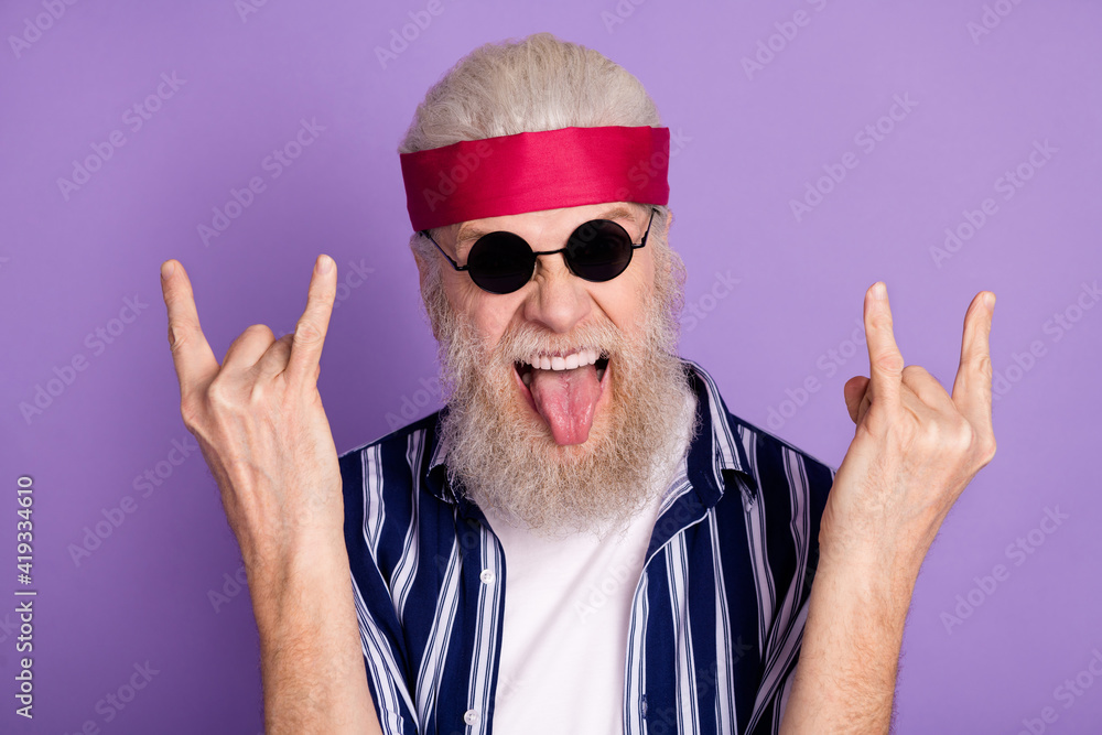 Naklejka premium Photo of aged man grimace fooling brutal tongue-out e show fingers rock sign isolated over violet color background