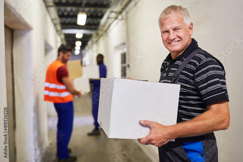 Lächelnder Arbeiter trägt Karton ins Warenlager