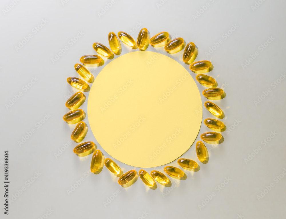 Vitamin D3 liquid capsules around yellow circle on neutral gray