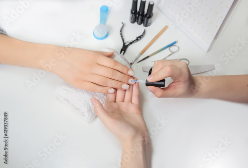 Manicurist is applying nail polish on a client s nail.