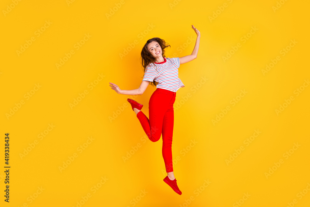 Photo of charming crazy lady jump enjoy wear striped shirt red pants shoes isolated yellow color background Photo of charming crazy lady jump enjoy wear striped shirt red pants shoes isolated yellow color background
