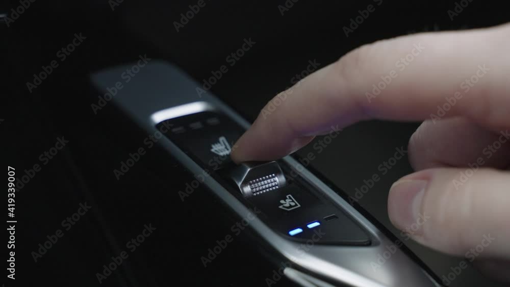 The man turns on the seat ventilation in the car. Comfortable car in hot weather seat cooling button The man turns on the seat ventilation in the car. Comfortable car in hot weather seat cooling button