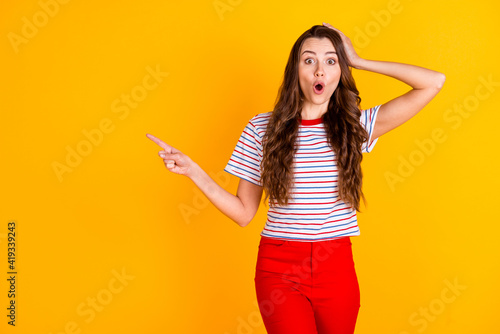 Photo of young excited girl amazed surprised indicate finger empty space ad advice suggest sale isolated over yellow color background