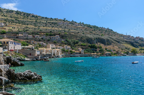 view of Limeni village with fishing boats in turquoise waters and the stone buildings as a background in Mani, South Peloponnese , Greece.