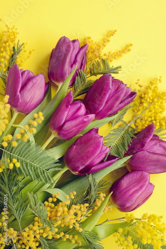 Vertical composition of lilac tulips and mimosa on a yellow background. Top view © Валерия Зеленева