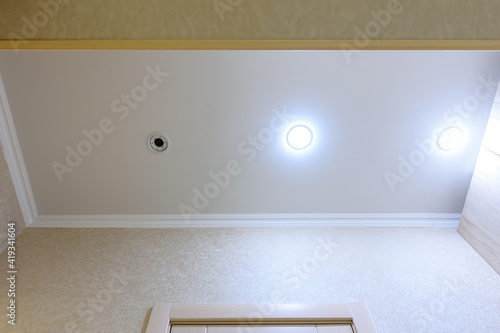 Bild auf Leinwand Stretch white matte ceiling in the hallway, one of the lamps burned out and twis