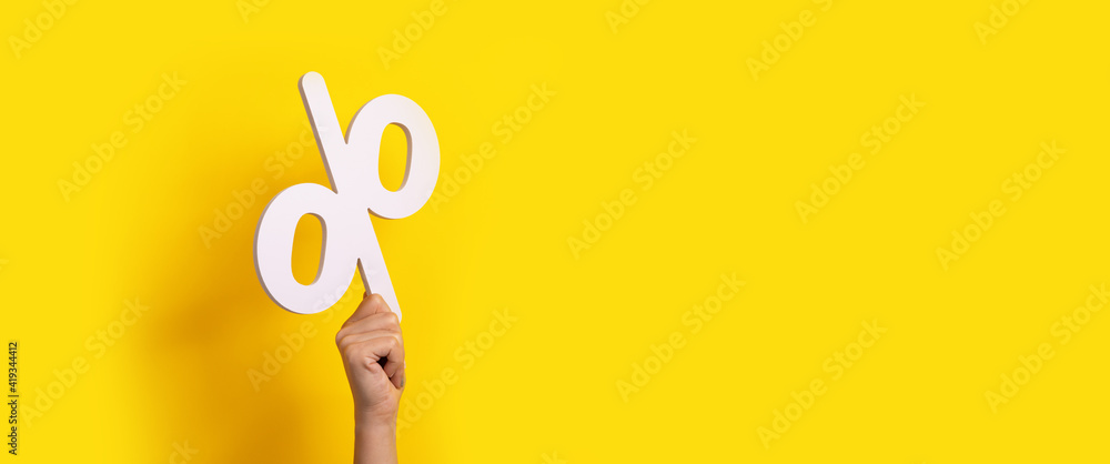 Fototapeta premium percentage sign in hand over yellow background, panoramic image