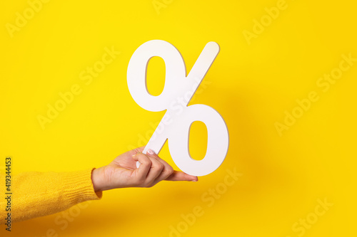 hand holding percentage sign over yellow background