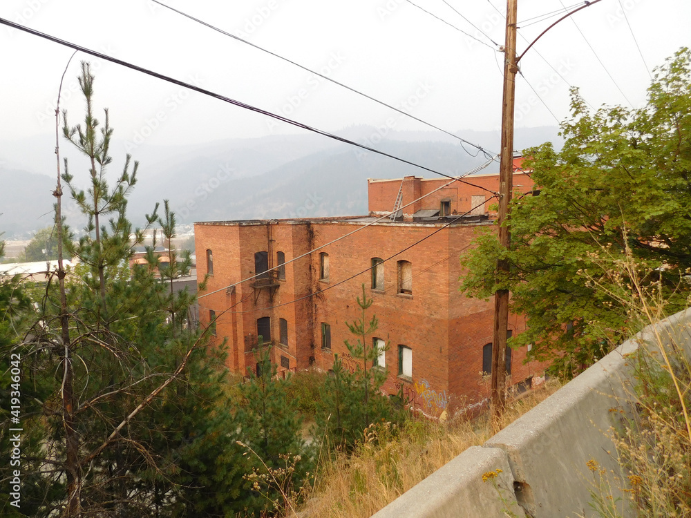 The back view of a red brick building in Keoogg, Idaho. Fog almost obscures the adjacent mountains in the distance.