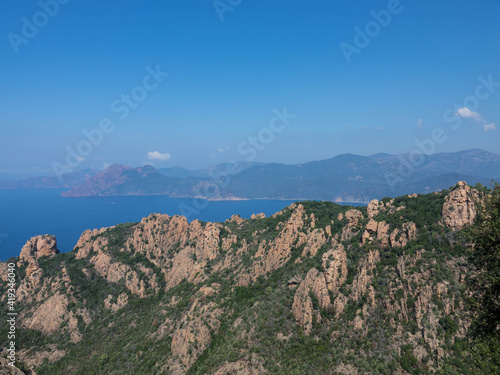 Aerial video from Calanques de Piana. Corsica red rocks located in Piana, between Ajaccio and Calvi. Over the Mountains range we see the Golf of Porto. Tourism and vacations concept. photo