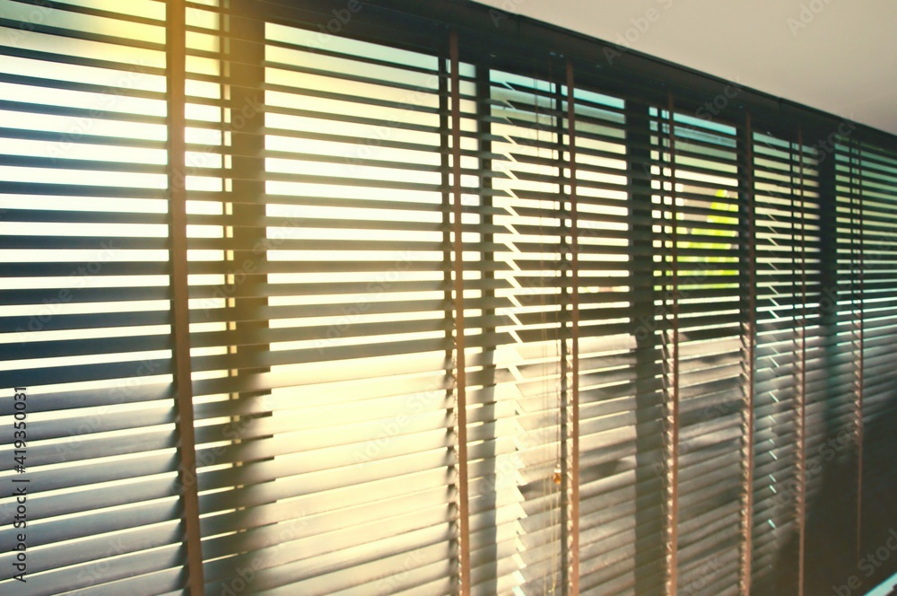 Fototapeta Evening sun light outside wooden window blinds, sunshine and shadow on window blinds , decorative interior home concept