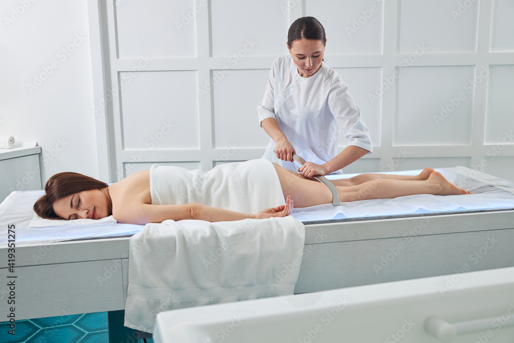 Fototapeta premium Female on a massage couch enjoying gua sha leg massage