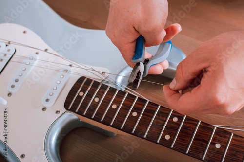 Guitar master restringing electric guitar, top view, closeup photo