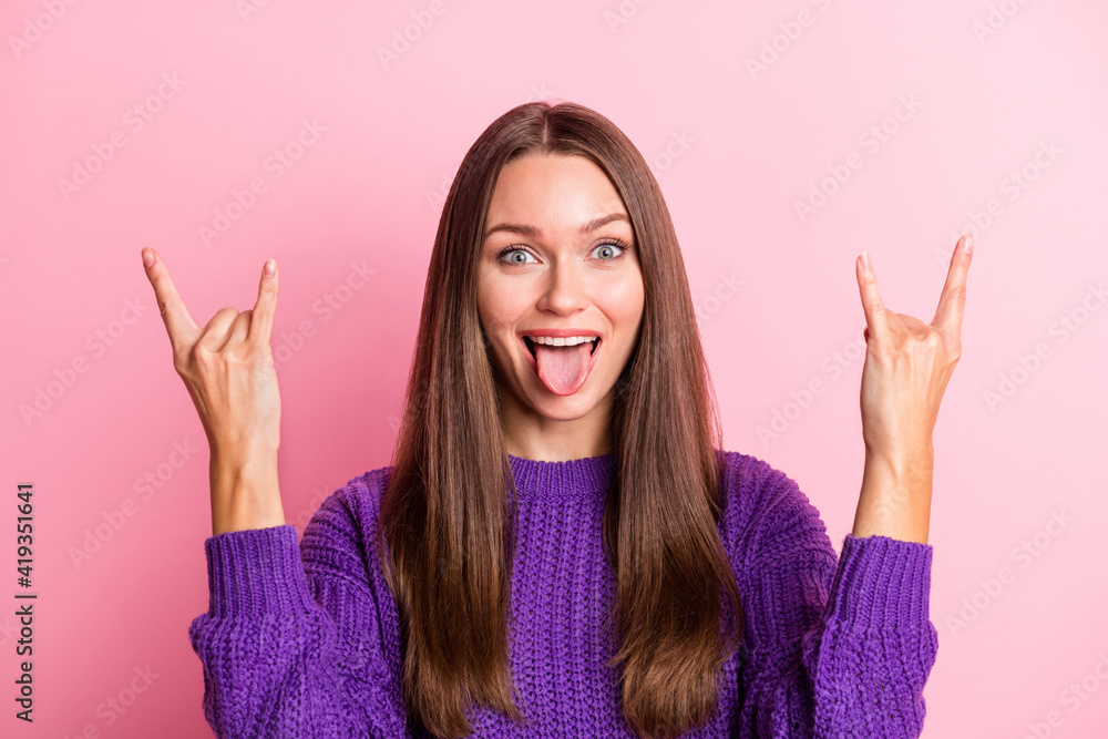 Portrait of optimistic girl show rock sign tongue out wear lilac sweater isolated on pastel pink color background Portrait of optimistic girl show rock sign tongue out wear lilac sweater isolated on pastel pink color background