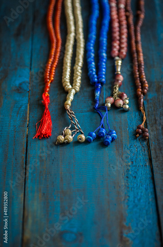 Various types of prayer beads or rosaries placed in a row on dark blue background. Conceptual image for religious harmony and togetherness.