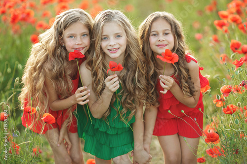 Group of happy children playing outdoors. Children have fun in the spring park. Girls run in the field with poppies. High quality photo.
