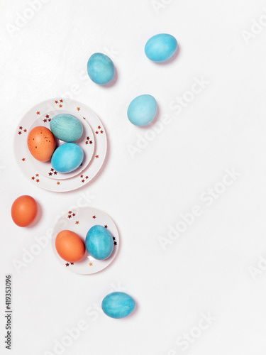 Colored eggs on plate with on white background. Flat lay. Copy space. Easter concept. Top view.