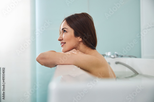 Dreaming woman staring far away from bathtub