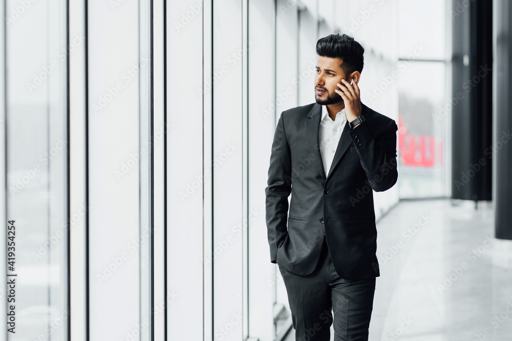 Portrait of a modern Indian man, Asian appearance, he steps on a business meeting, office worker, bank employee, boss. Holding Portrait of a modern Indian man, Asian appearance, he steps on a business meeting, office worker, bank employee, boss. Holding