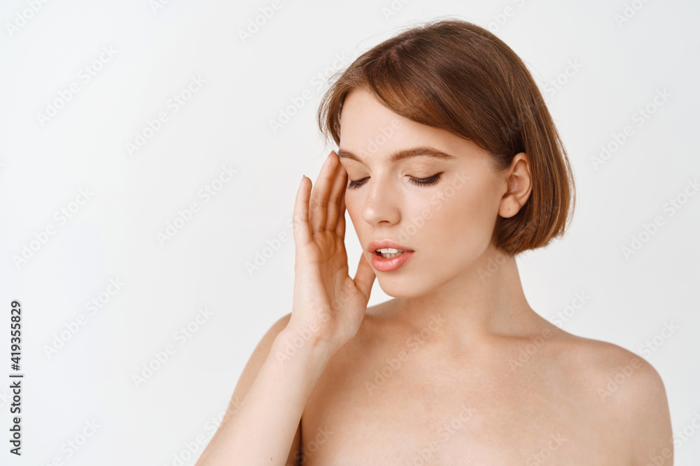 Skin care beauty. Sensual young woman, naked shoulders, look aside and show natural beautiful face without make-up, nourish and apply skin care products for hydrated and detoxifying effect Skin care beauty. Sensual young woman, naked shoulders, look aside and show natural beautiful face without make-up, nourish and apply skin care products for hydrated and detoxifying effect