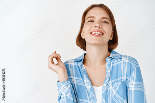 Portrait of happy smiling woman  laughing and looking relaxed at camera  standing in casual clothes against white background