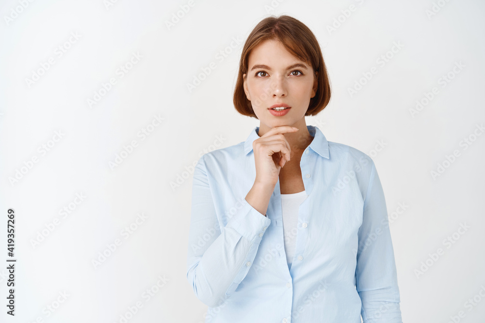 Getting inspiration. Portrait of young ceo female manager looking at camera thoughtful, have an idea, touching chin and pondering plan, standing on white background Getting inspiration. Portrait of young ceo female manager looking at camera thoughtful, have an idea, touching chin and pondering plan, standing on white background