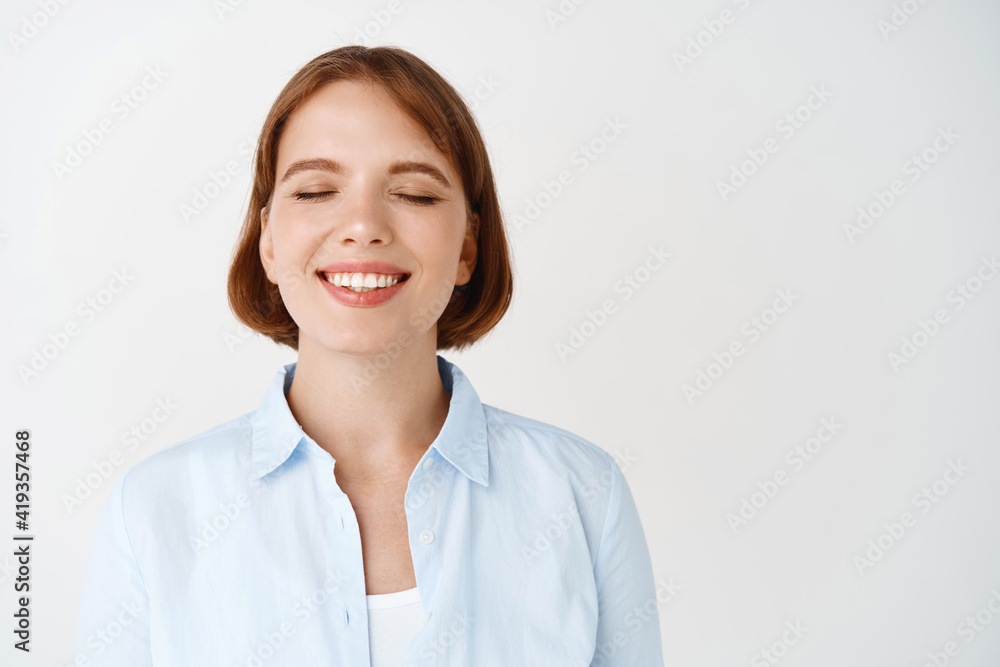 Portrait of dreamy smiling young woman, close eyes and daydreaming, standing in blouse against white background Portrait of dreamy smiling young woman, close eyes and daydreaming, standing in blouse against white background
