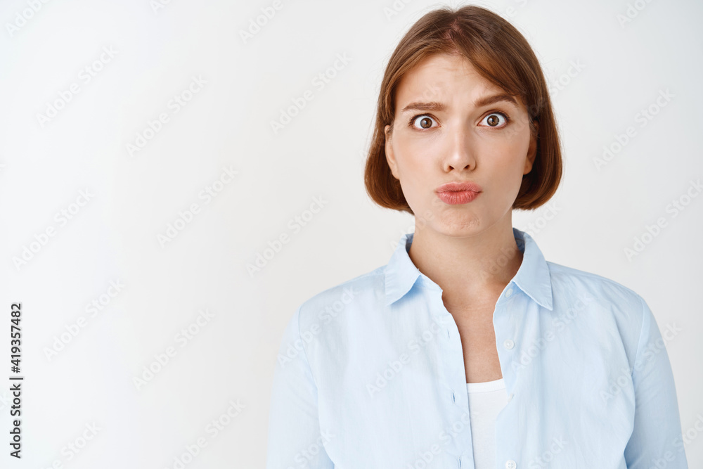 Portrait of confused young woman raising eyebrows and pucker lips puzzled, cant understand, standing in stupor on white background. Girl grimacing clueless Portrait of confused young woman raising eyebrows and pucker lips puzzled, cant understand, standing in stupor on white background. Girl grimacing clueless