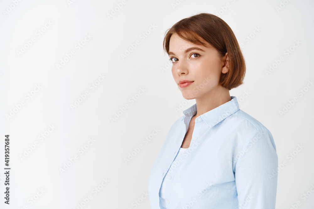 Portrait of young businesswoman in blouse with short natural hair, looking at camera and smile, standing against white background Portrait of young businesswoman in blouse with short natural hair, looking at camera and smile, standing against white background