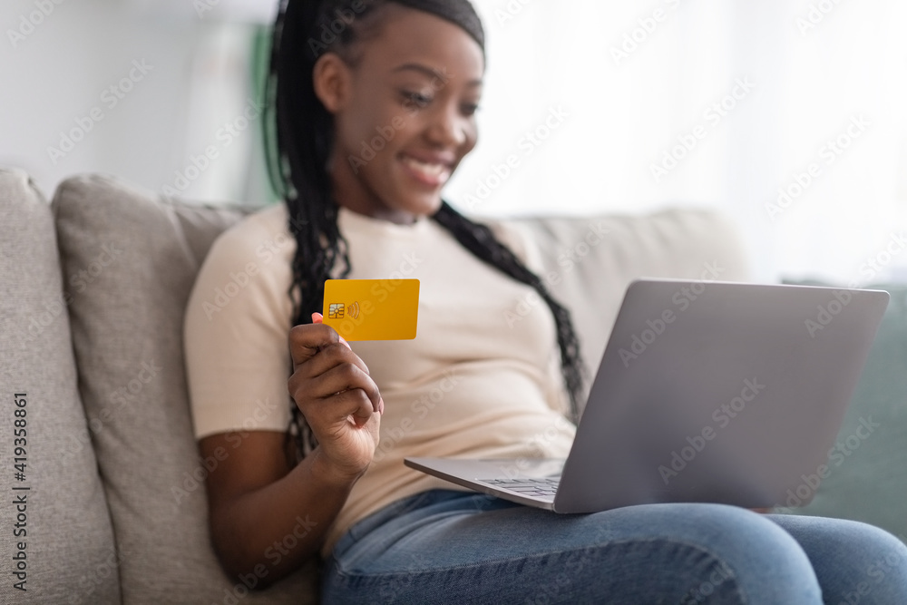 Closeup of positive black woman holding credit card, using laptop Closeup of positive black woman holding credit card, using laptop