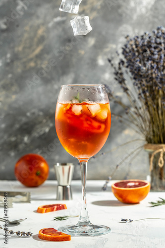 Glass of Aperol spritz cocktail on gray background. Italian cocktail with bloody oranges