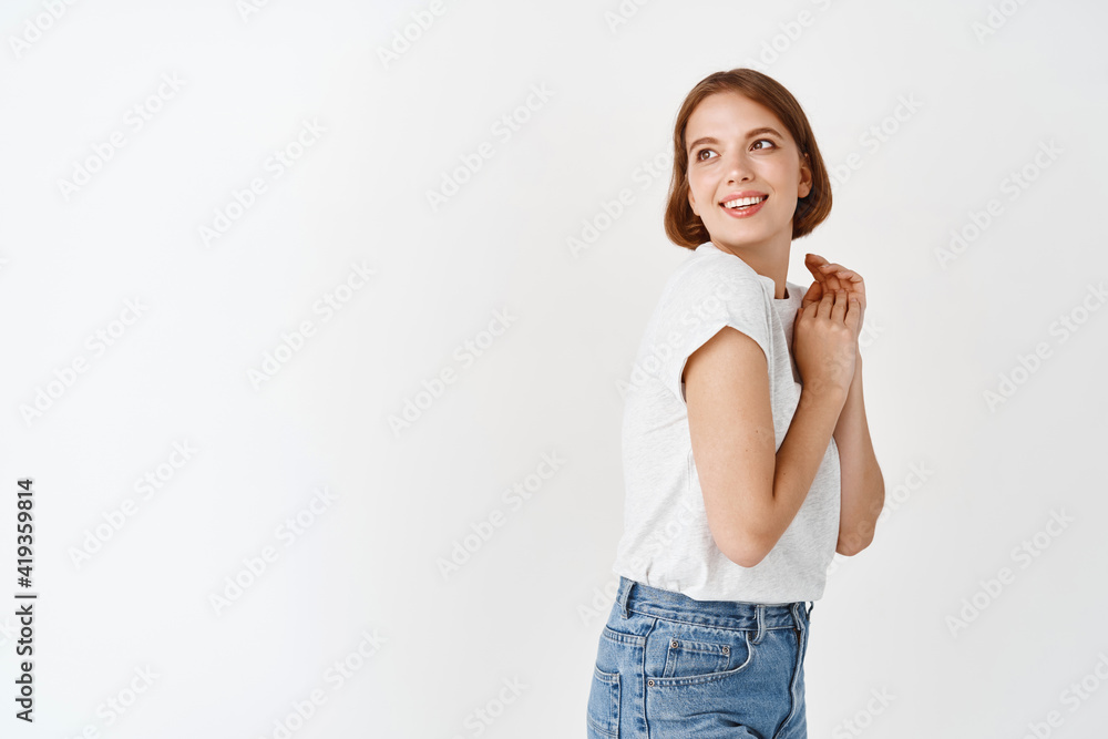 Beautiful tender girl gazing with affection and care, looking aside and smiling cute, holding hands pressed together, standing against white background Beautiful tender girl gazing with affection and care, looking aside and smiling cute, holding hands pressed together, standing against white background