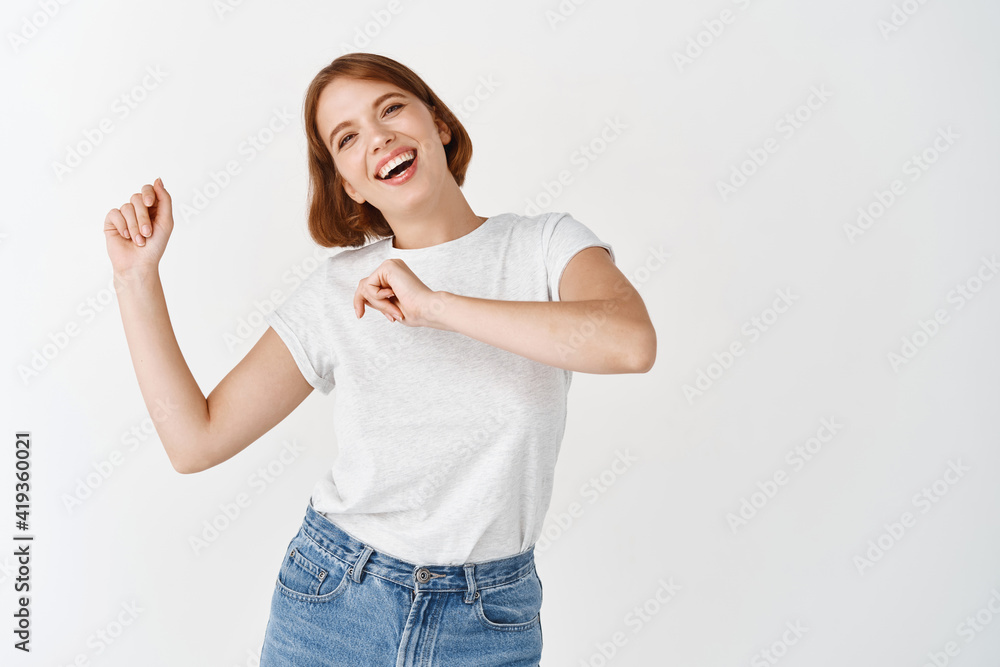 Happy woman dancing and having fun, laughing joyful at camera, standing against white background Happy woman dancing and having fun, laughing joyful at camera, standing against white background