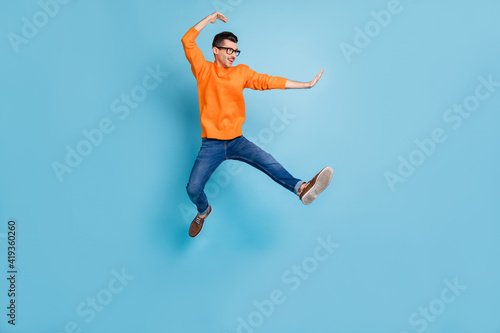 Full body profile photo of cheerful man jumping high have fun wear sweater isolated on blue color background
