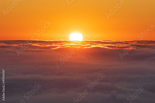 Obraz na plátně Sol emergiendo sobre mar de nubes, cielo totalmente naranja