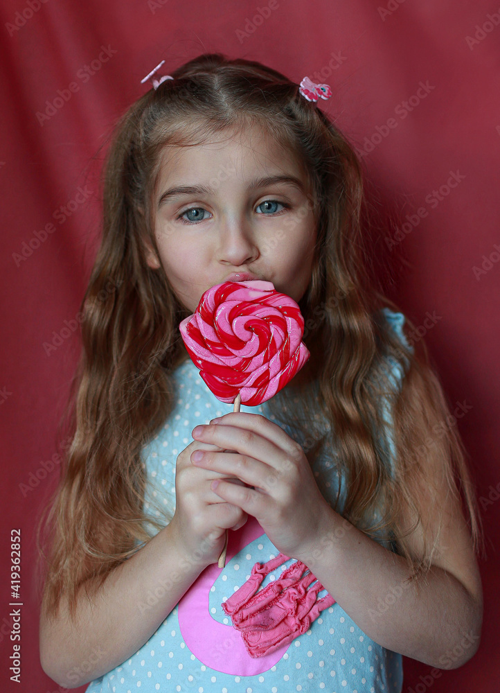 Little cute kid girl eating big candy on a stick