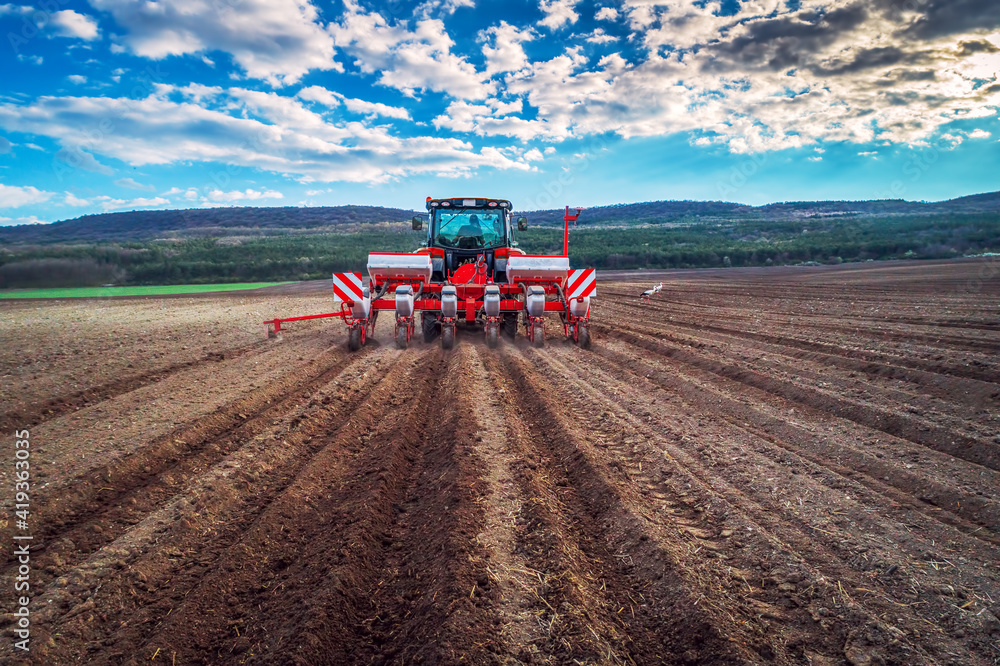 Fototapeta premium Farmer with tractor seeding crops at field