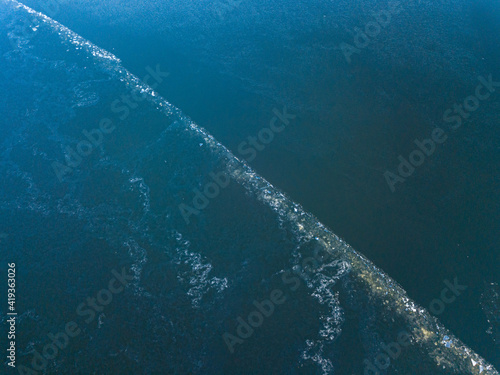 Frosty pattern on the river. Aerial drone view. Sunny winter day, thin ice on the river.