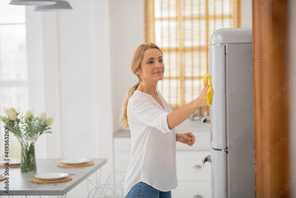 Cute blonde housewife cleaning the fridge