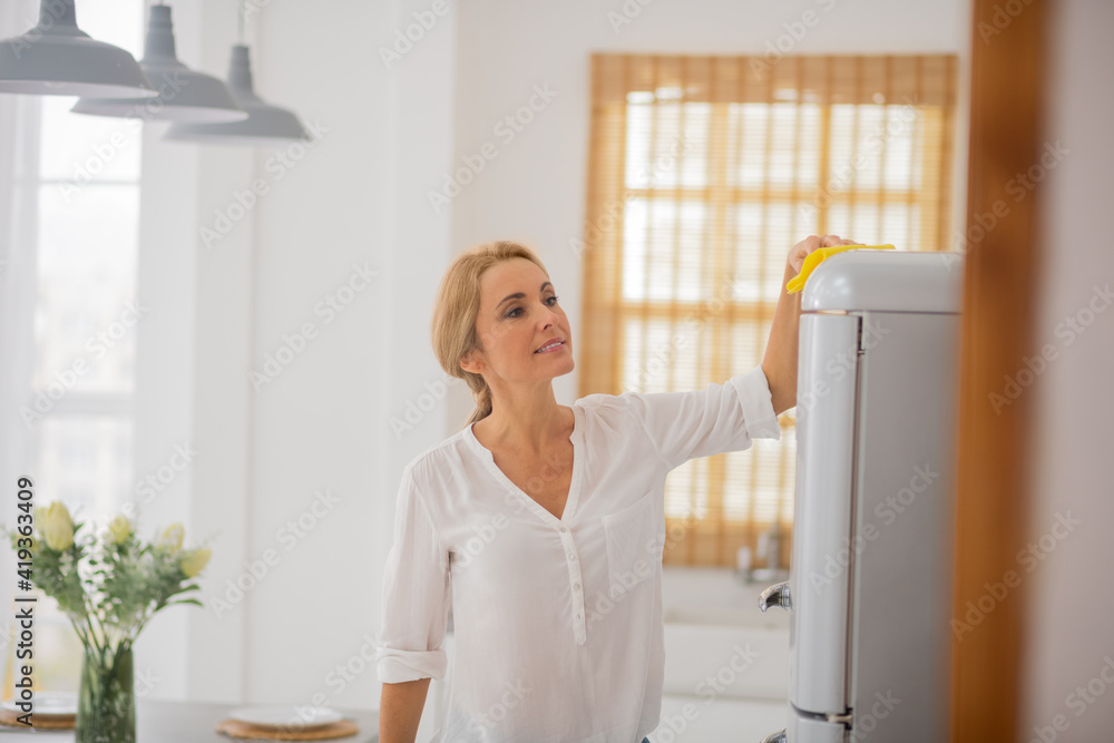 Cute blonde housewife cleaning the fridge and looking involved Cute blonde housewife cleaning the fridge and looking involved