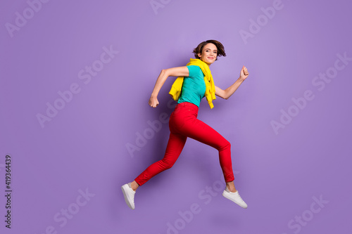 Full length photo of girl jump run wear tied sweater t-shirt pants sneakers isolated violet color background