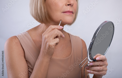 фотографія Cropped view of mature woman removing unwanted hair from her chin, using tweezer
