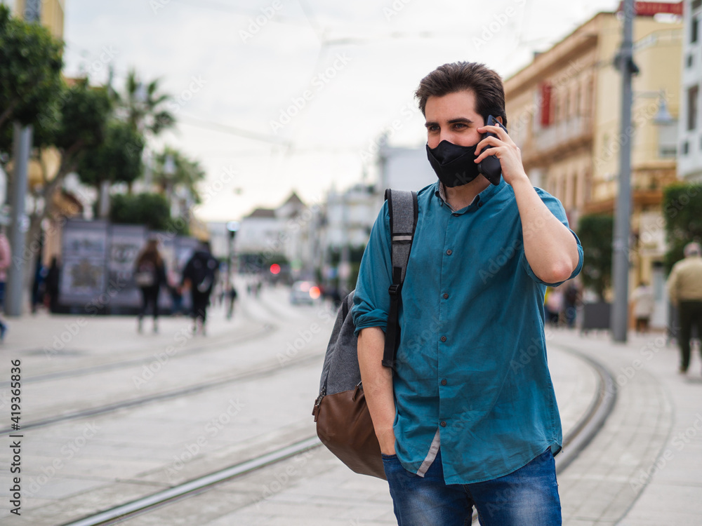 Hombre joven usando su movil con mascarilla Hombre joven usando su movil con mascarilla